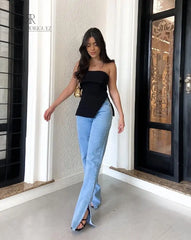 Mujer vistiendo la blusa negra strapless Paulina, combinada con jeans de corte recto, destacando un estilo moderno y elegante