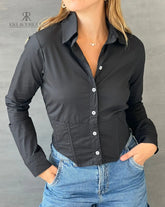 Mujer vistiendo una blusa crop top negra con botones blancos, ideal para un look elegante y moderno. Disponible en KIKE RODRIGUEZ.
