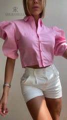Mujer vistiendo una blusa crop top rosa con mangas abullonadas, ideal para un look chic y moderno. Disponible en KIKE RODRIGUEZ.