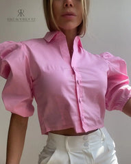 Mujer vistiendo una blusa crop top rosa con mangas abullonadas, ideal para un look chic y moderno. Disponible en KIKE RODRIGUEZ.