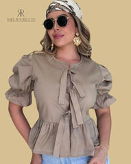 Mujer vistiendo la Blusa Sofía Nude de Kike Rodriguez con diseño peplum, lazos frontales y mangas tres cuartos, ideal para un look casual y elegante