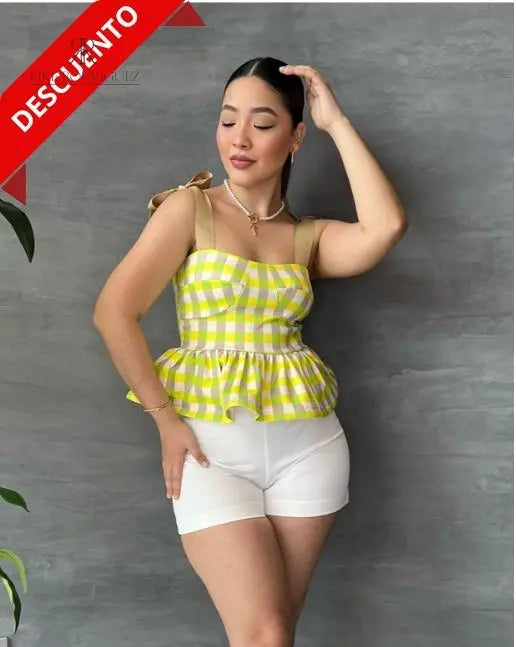 Mujer con una blusa de cuadros amarillos y volantes en descuento, mostrando un estilo alegre y moderno, perfecta para cualquier ocasión.