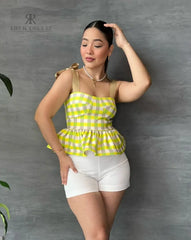 Mujer con una blusa de cuadros amarillos y volantes en descuento, mostrando un estilo alegre y moderno, perfecta para cualquier ocasión.