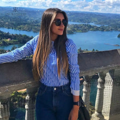 Mujer con blusa de rayas con espalda descubierta disfrutando de una vista panorámica. Blusa perfecta para un look casual y sofisticado. Disponible en KIKE RODRIGUEZ.