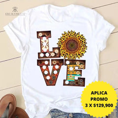 Camiseta blanca con el texto "LOVE" en diseño floral, disponible en promoción especial de 3 por $129,900. Perfecta para un estilo casual y moderno, presentada por KIKE RODRIGUEZ.