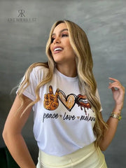 Camiseta blanca con diseño dorado de "Peace Love Melanin", en promoción especial de 3 por $129,900 en KIKE RODRIGUEZ. Ideal para expresar estilo y un mensaje positivo.