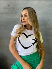 Camiseta blanca con diseño de corazón y avión en promoción especial de 3 por $129,900, disponible en KIKE RODRIGUEZ. Ideal para los amantes de los viajes y la moda.