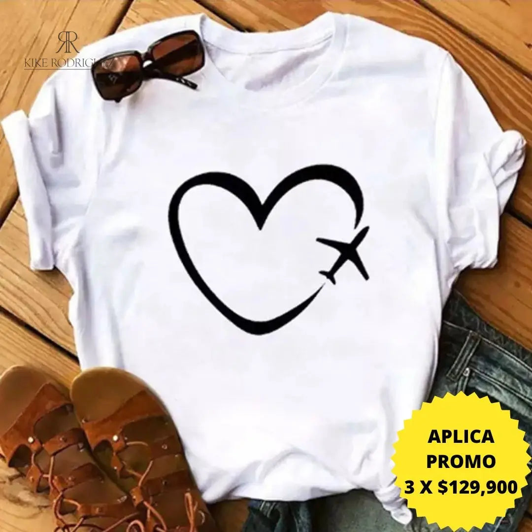 Camiseta blanca con diseño de corazón y avión en promoción especial de 3 por $129,900, disponible en KIKE RODRIGUEZ. Ideal para los amantes de los viajes y la moda.