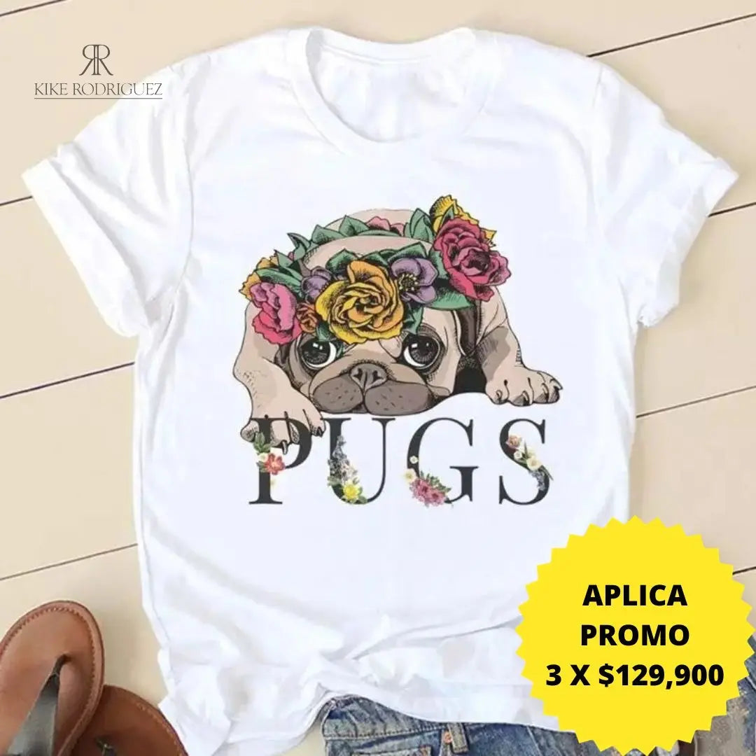 Camiseta blanca con un estampado adorable de pug con flores. Disponible en promoción de 3 por $129,900 en KIKE RODRIGUEZ. Perfecta para un look casual y divertido. ¡Ideal para amantes de los perros!