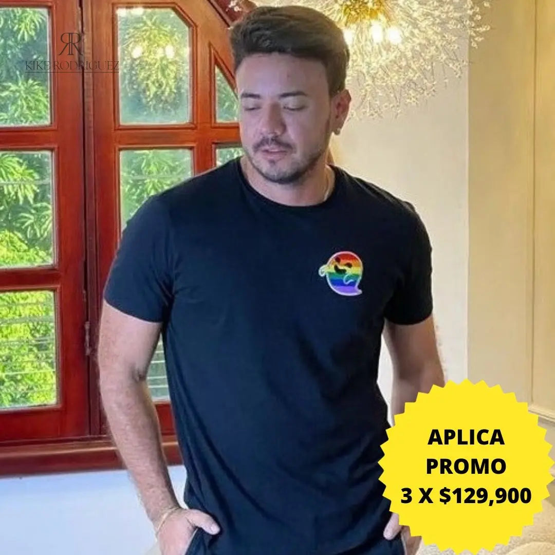 Camiseta negra con un pequeño estampado de arcoíris en el pecho. Perfecta para un look casual y elegante. Disponible en promoción de 3 por $129,900 en KIKE RODRIGUEZ. Ideal para mostrar apoyo a la diversidad.