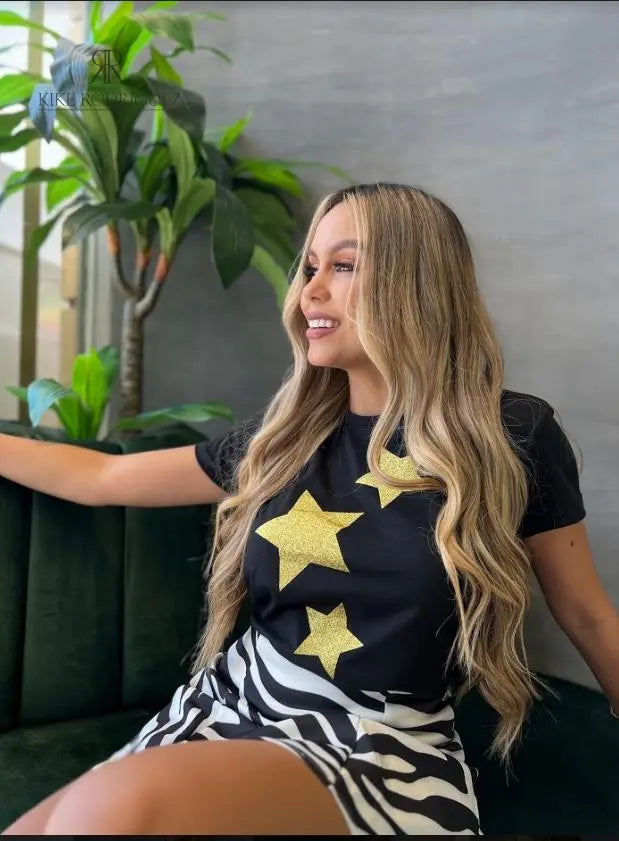 Camiseta negra con diseño de estrellas doradas de brillo, disponible en promoción especial de 3 por $129,900 en KIKE RODRIGUEZ. Ideal para un estilo glamuroso y moderno.