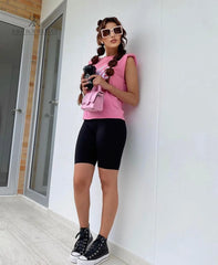 Modelo luciendo una camiseta rosa Barbie con estilo casual y moderno, combinada con leggings negros y accesorios a la moda, ideal para un look relajado y chic.