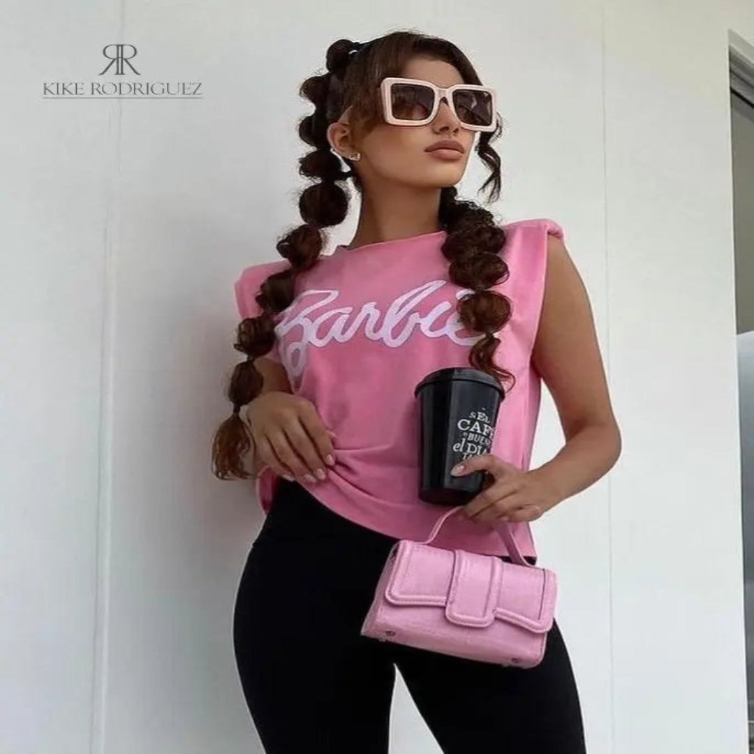 Modelo luciendo una camiseta rosa Barbie con estilo casual y moderno, combinada con leggings negros y accesorios a la moda, ideal para un look relajado y chic.