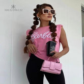 Modelo luciendo una camiseta rosa Barbie con estilo casual y moderno, combinada con leggings negros y accesorios a la moda, ideal para un look relajado y chic.