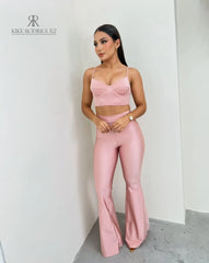 Mujer vistiendo un conjunto rosa sexy de KIKE RODRIGUEZ, compuesto por un top ajustado y pantalones acampanados.
