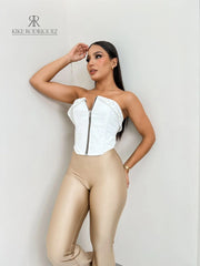 Mujer vistiendo un corset blanco con cierre frontal y detalle de tachuelas, ideal para un look atrevido y moderno. Disponible en KIKE RODRIGUEZ.