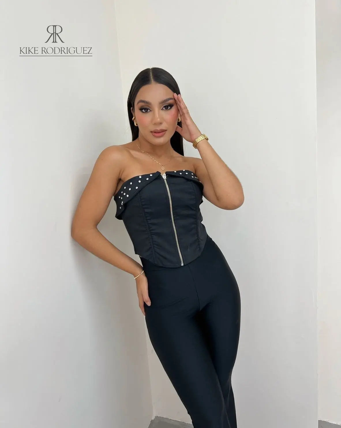 Mujer vistiendo un corset negro con cierre frontal y detalle de tachuelas, ideal para un look atrevido y moderno. Disponible en KIKE RODRIGUEZ.