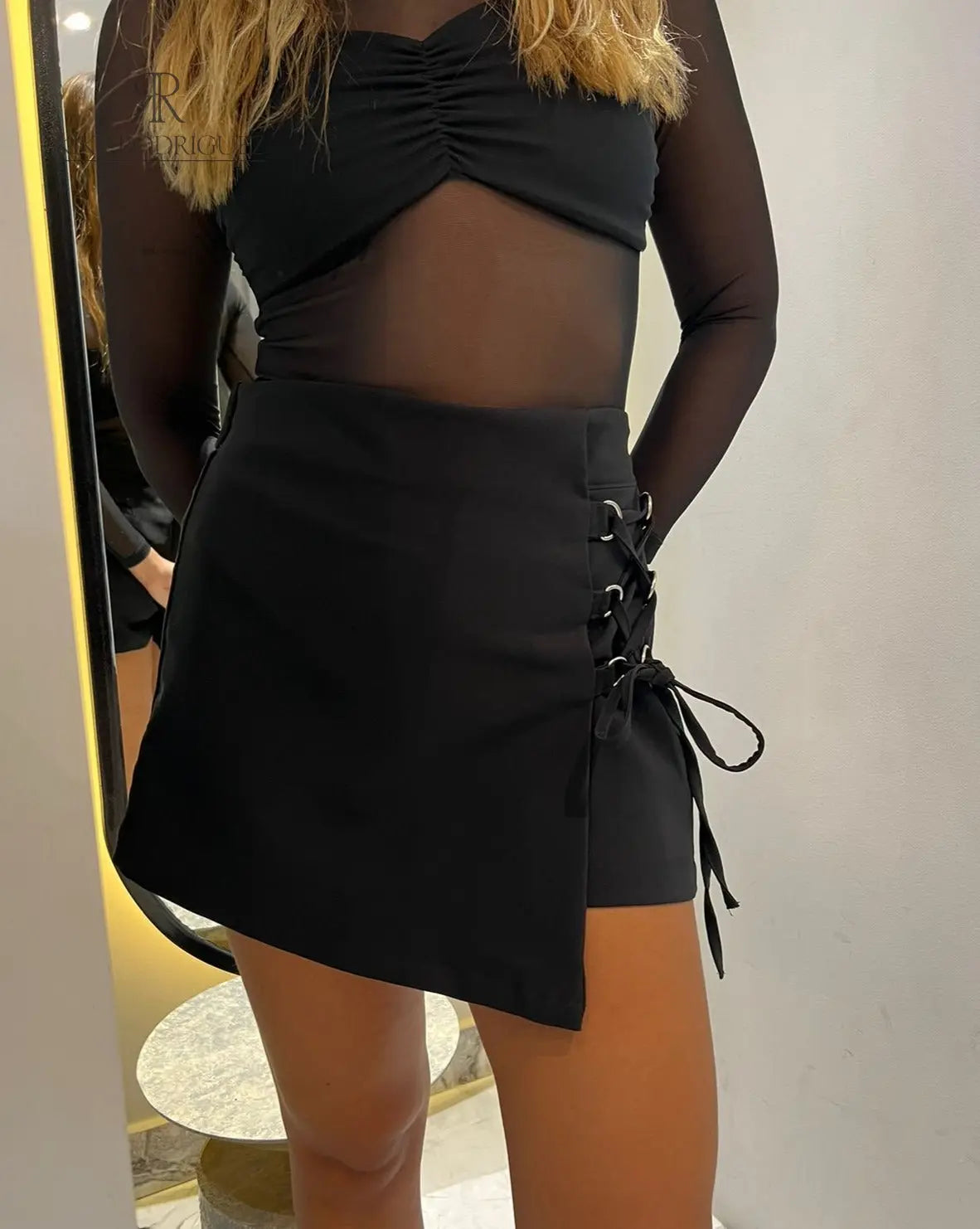 Falda asimétrica negra con detalles de cordón en el lateral, perfecta para un look sofisticado y moderno.