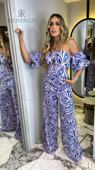 Modelo luciendo un moderno enterizo con estampado azul y rosa, escote halter y mangas abullonadas, ideal para destacar en cualquier evento.