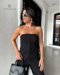 Mujer vistiendo un set negro elegante de KIKE RODRIGUEZ, compuesto por un top sin tirantes y pantalones de pierna ancha, ideal para eventos formales.