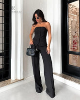 Mujer vistiendo un set negro elegante de KIKE RODRIGUEZ, compuesto por un top sin tirantes y pantalones de pierna ancha, ideal para eventos formales.