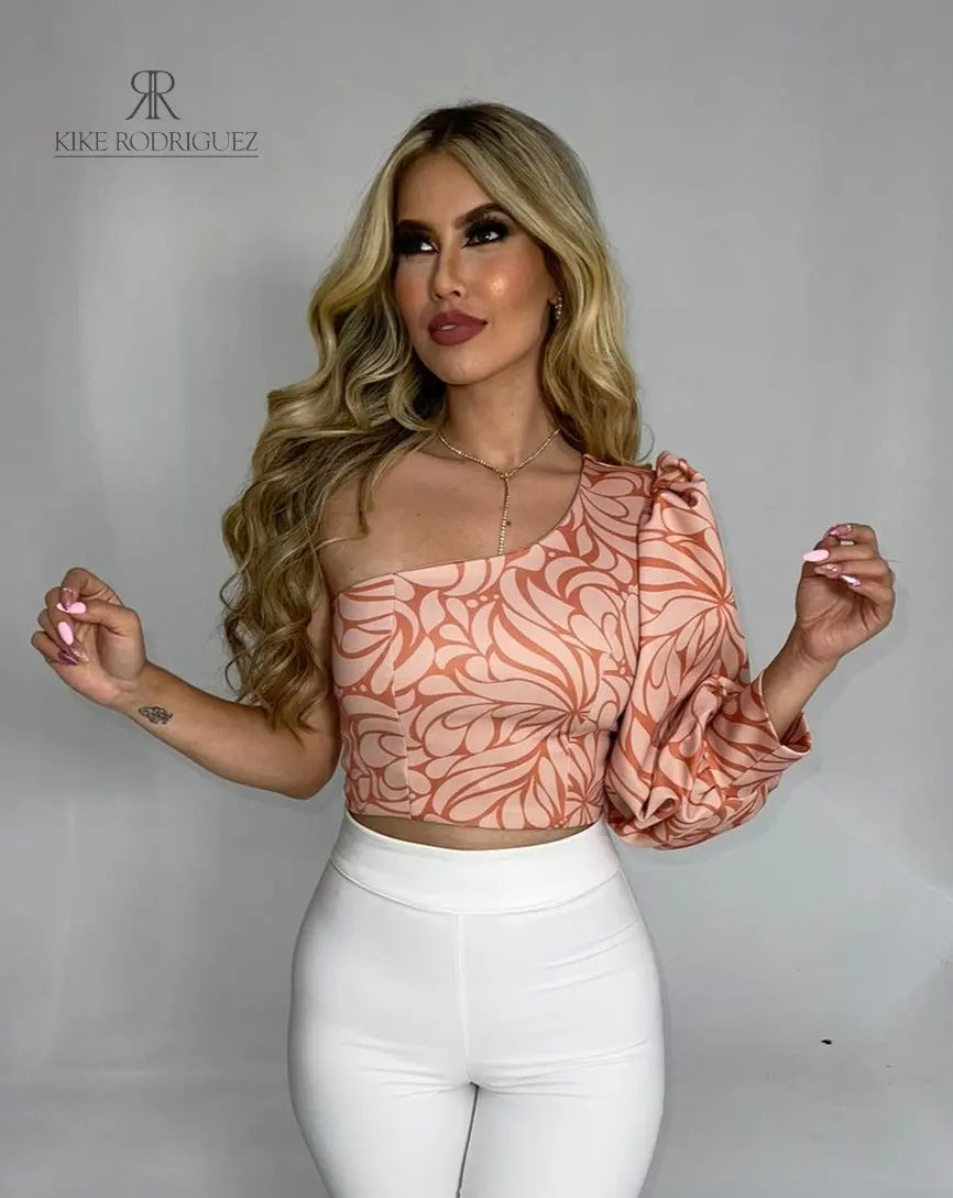 Mujer luciendo un top asimétrico con estampado floral en tonos rosados, con una manga larga abullonada, ideal para un look elegante y moderno.