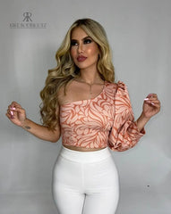 Mujer luciendo un top asimétrico con estampado floral en tonos rosados, con una manga larga abullonada, ideal para un look elegante y moderno.