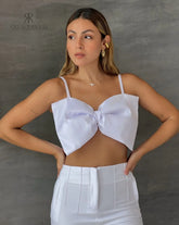 Mujer luciendo un top blanco con lazo frontal, ideal para un look elegante y sofisticado. Perfecto para cualquier ocasión especial.