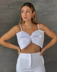 Mujer luciendo un top blanco con lazo frontal, ideal para un look elegante y sofisticado. Perfecto para cualquier ocasión especial.