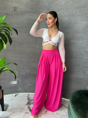 Mujer luciendo un top blanco con mangas de malla y detalles cruzados, combinado con una falda rosa, ideal para un look moderno y elegante.