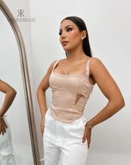 Mujer luciendo un top nude con tirantes y diseño lateral, perfecto para un look sofisticado y elegante. Disponible en KIKE RODRIGUEZ.