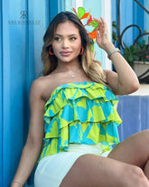 Mujer luciendo un top sin tirantes con volantes en verde y azul, perfecto para un look fresco y llamativo. Disponible en KIKE RODRIGUEZ.