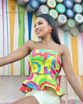 Mujer vistiendo un top strapless colorido con diseño abstracto, ideal para un look vibrante y moderno. Disponible en KIKE RODRIGUEZ.