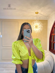 Top verde neón satinado con mangas abullonadas, perfecto para destacar en eventos especiales, combinado con jeans para un look moderno y llamativo.