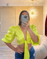 Top verde neón satinado con mangas abullonadas, perfecto para destacar en eventos especiales, combinado con jeans para un look moderno y llamativo.