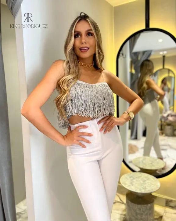 Mujer vistiendo un top de flecos plateado de KIKE RODRIGUEZ, ideal para noches de fiesta y eventos especiales, que añade un toque de glamour y brillo a su atuendo.