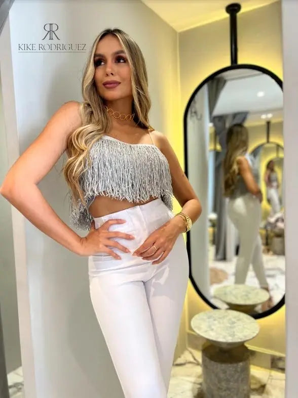 Mujer vistiendo un top de flecos plateado de KIKE RODRIGUEZ, ideal para noches de fiesta y eventos especiales, que añade un toque de glamour y brillo a su atuendo.