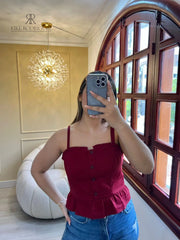 Mujer usando un top de tirantes rojo con botones y volantes, perfecto para un look casual y elegante, ideal para cualquier ocasión.