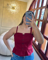 Mujer usando un top de tirantes rojo con botones y volantes, perfecto para un look casual y elegante, ideal para cualquier ocasión.