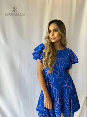 Mujer con un vestido azul rey con volantes y bolsillos de KIKE RODRIGUEZ, perfecto para cualquier ocasión y evento elegante.