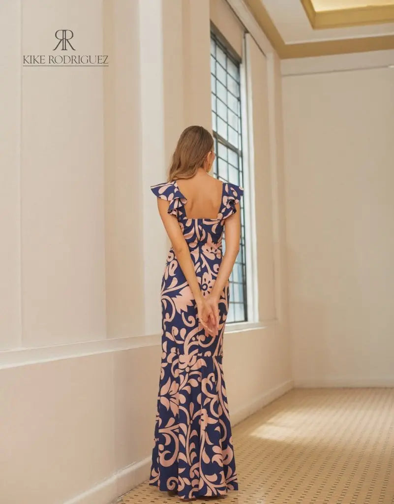 Mujer vistiendo un elegante vestido largo estampado floral en tonos azul y rosa de KIKE RODRIGUEZ, ideal para ocasiones especiales y eventos formales.