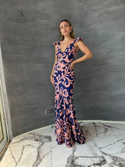 Mujer vistiendo un elegante vestido largo estampado floral en tonos azul y rosa de KIKE RODRIGUEZ, ideal para ocasiones especiales y eventos formales.