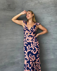 Mujer vistiendo un elegante vestido largo estampado floral en tonos azul y rosa de KIKE RODRIGUEZ, ideal para ocasiones especiales y eventos formales.
