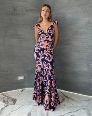 Mujer vistiendo un elegante vestido largo estampado floral en tonos azul y rosa de KIKE RODRIGUEZ, ideal para ocasiones especiales y eventos formales.