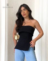 Mujer usando blusa negra strapless Paulina, combinada con jeans azules, mostrando un look elegante y moderno