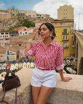Mujer con blusa de rayas rojas y blancas, estilo casual chic, ideal para looks veraniegos.