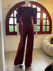 Vista lateral del enterizo burdeos mostrando mangas abullonadas y diseño de pierna ancha que estiliza la figura