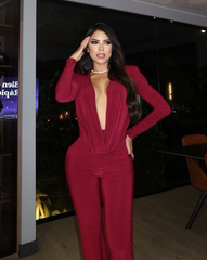 Mujer usando enterizo rojo profundo Nova Cherry de la colección Orión de KIKE RODRIGUEZ, con escote pronunciado y diseño palazzo ideal para eventos elegantes o de noche.