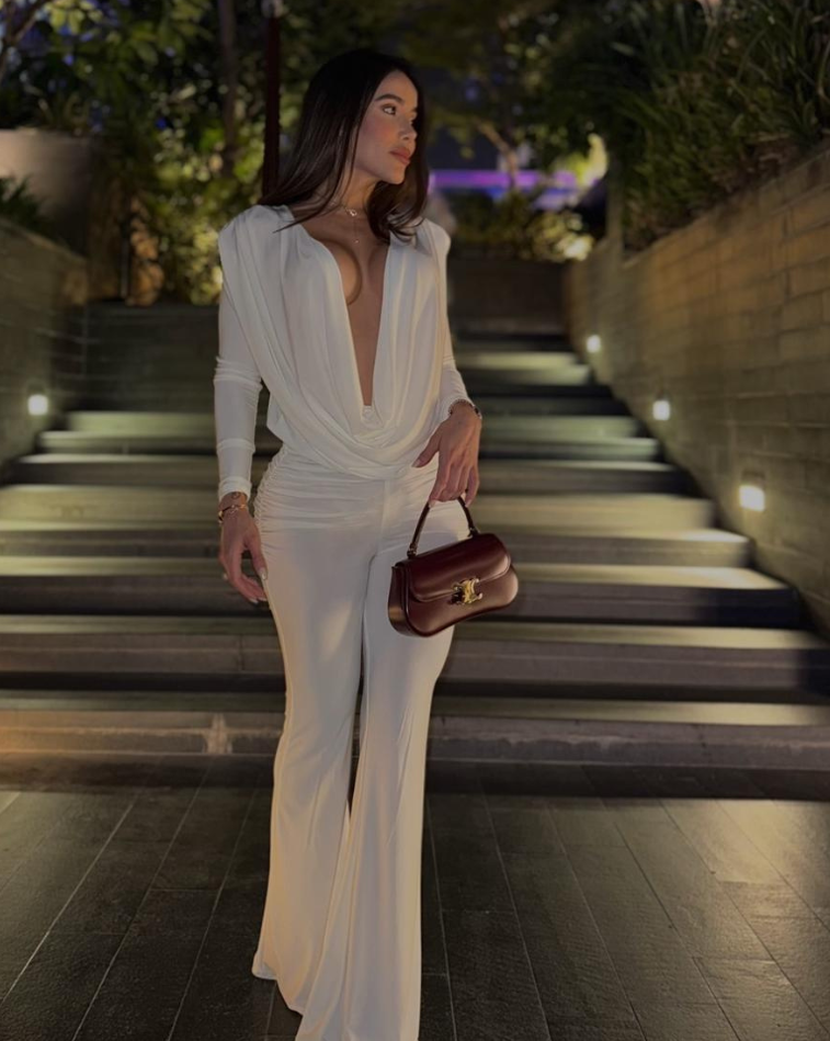 Mujer usando enterizo blancoNova Cherry de la colección Orión de KIKE RODRIGUEZ, con escote pronunciado y diseño palazzo ideal para eventos elegantes o de noche.