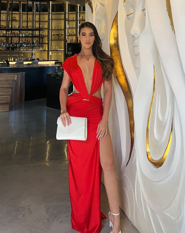 Vestido Victoria rojo largo de KIKE RODRIGUEZ con espalda descubierta y acabado satinado, vista posterior en restaurante elegante.